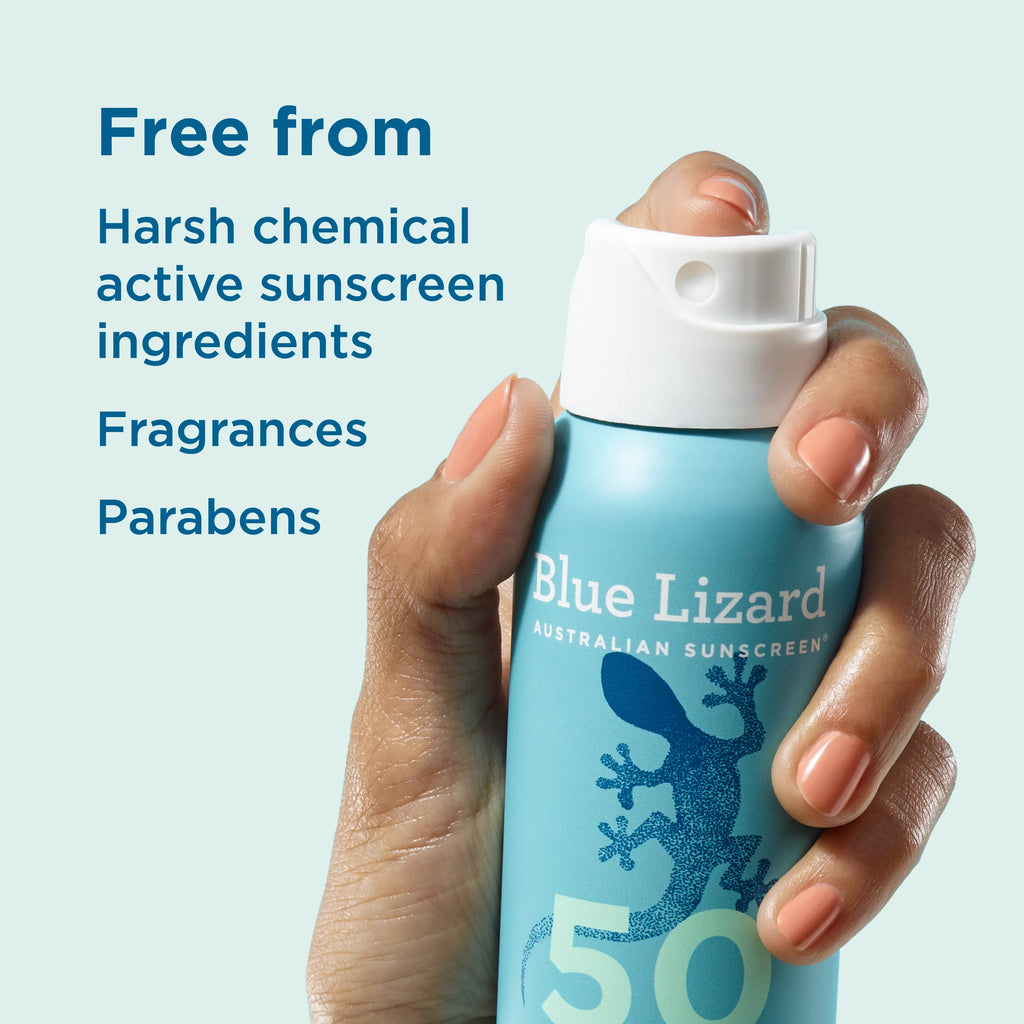 Hand holding Blue Lizard sensitive SPF50 mineral sunscreen spray can with text highlighting ingredients free from harsh chemicals on a light blue background